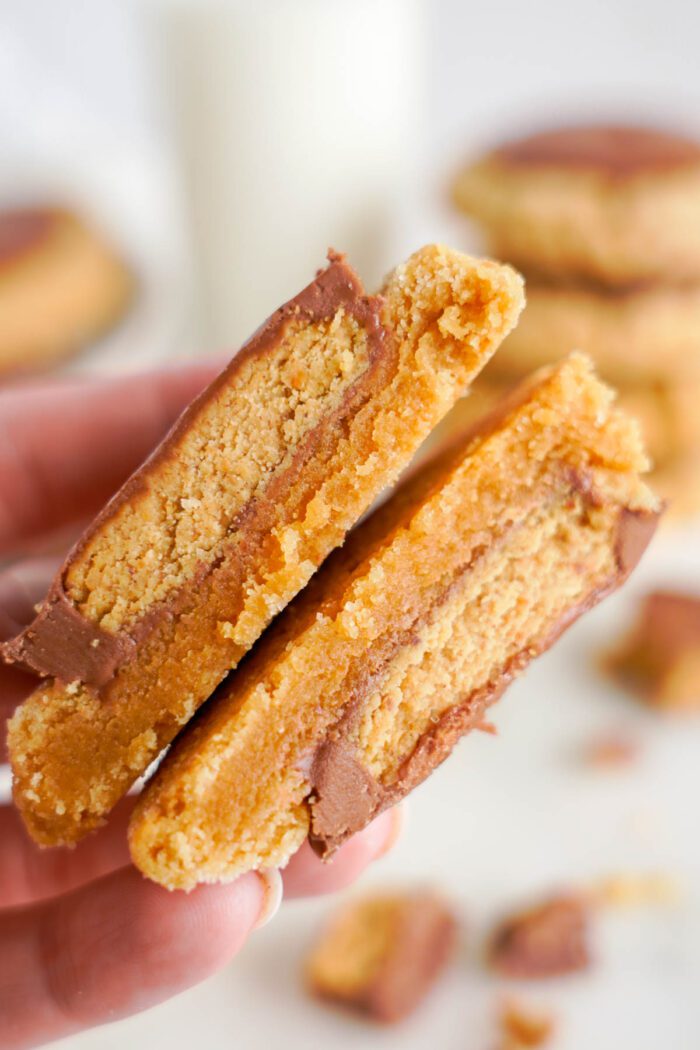 A close-up view of an easy peanut butter cup cookie sandwich cut in half, revealing a thick layer of chocolate filling.