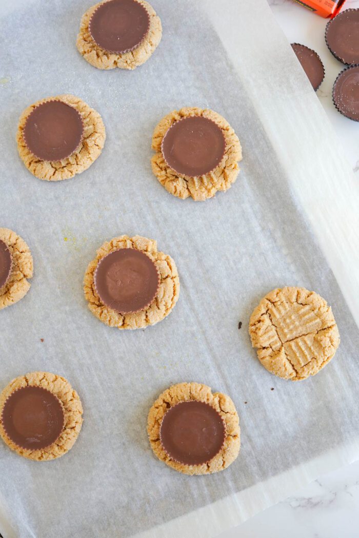 Easy peanut butter cookies with chocolate discs on top, laid out on parchment paper.