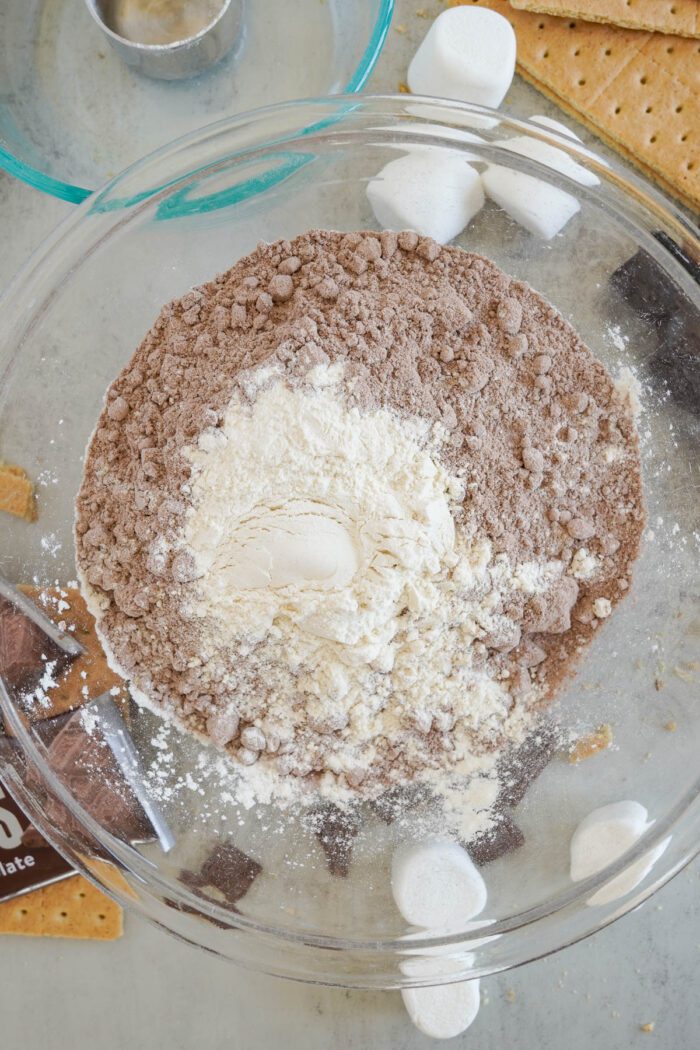 Top-down view of brownie mix and flour in a glass bowl for baking.