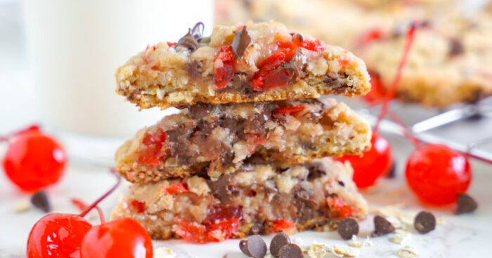 Stack of cherry chocolate chip cookie bars from a Cherry Chocolate Chip Cookies Recipe, with visible cherries and chocolate chips, served on a marble surface.