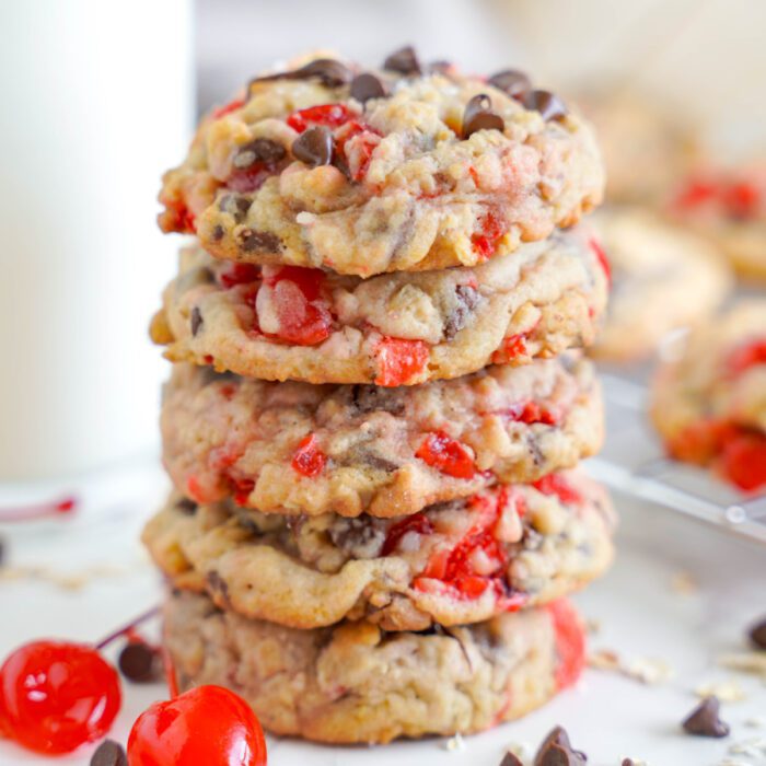 A Cherry Chocolate Chip Cookies Recipe for a stack of chocolate chip and cherry cookies with visible cherries and chocolate pieces, set against a blurred background.