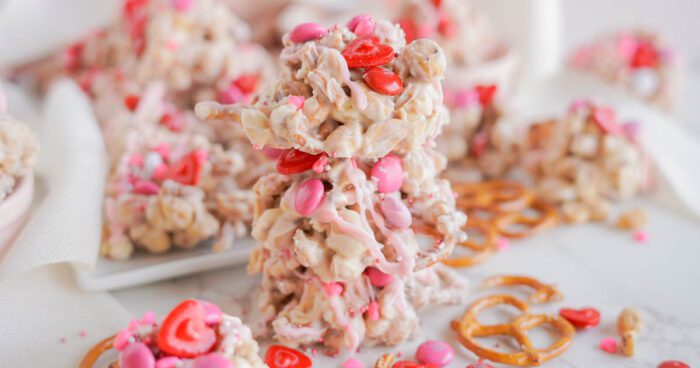 Valentine-themed white chocolate bark with pretzels and pink candies on a light tablecloth.
