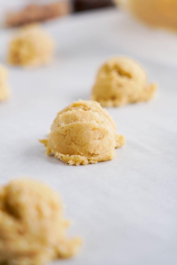 Scoops of cookie dough, perfect for an easy cookie dough cookies recipe, are arranged on a parchment-lined baking sheet.