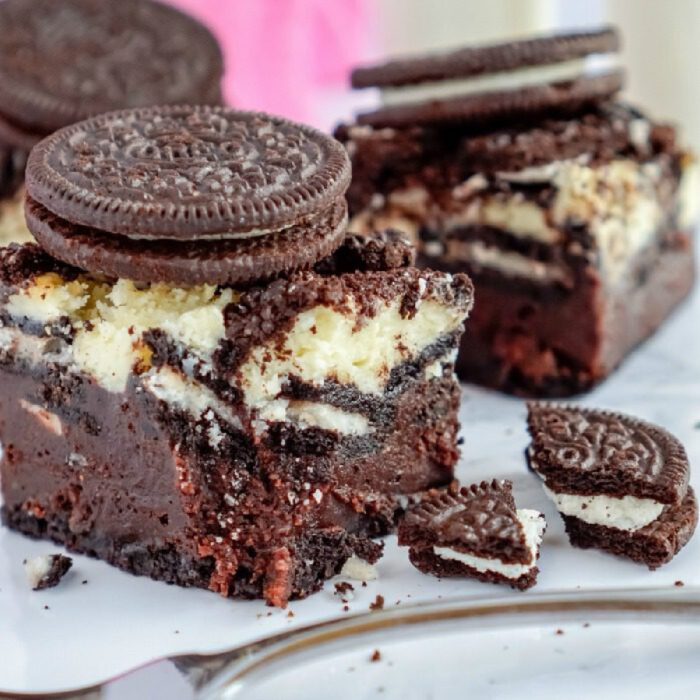 A close-up of a Oreo Dessert featuring chunks of Oreo cookies embedded in brownie and cheesecake.