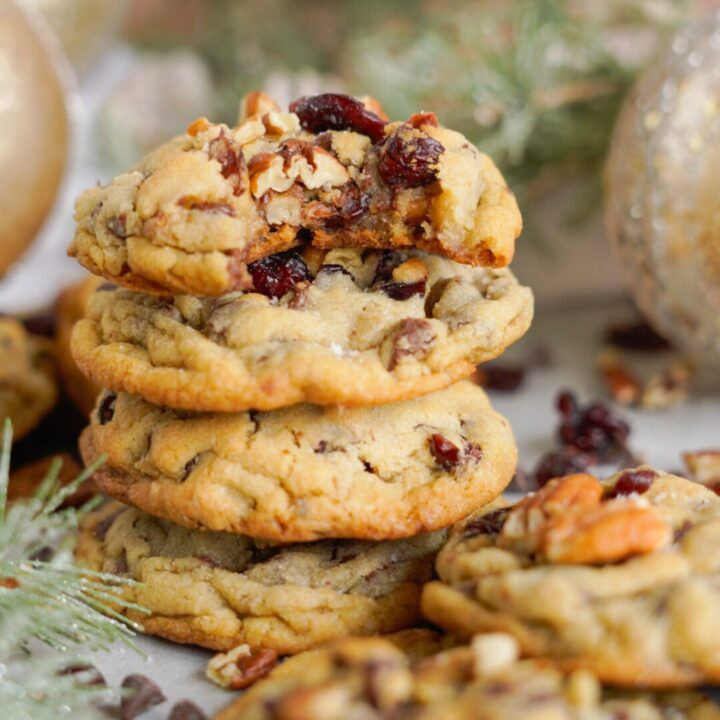 A stack of cranberry walnut cookies on a festive table adorned with holiday decorations.