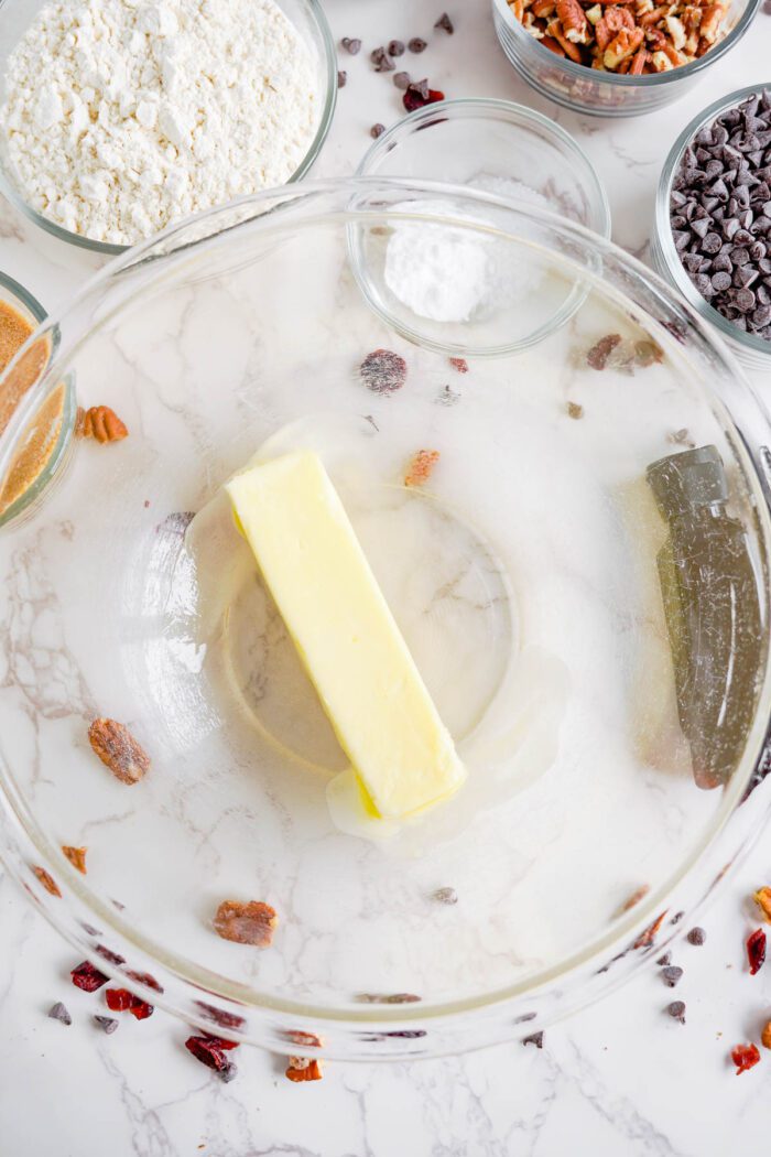 Ingredients for baking displayed on a kitchen counter, including butter in a glass bowl and flour in a container.