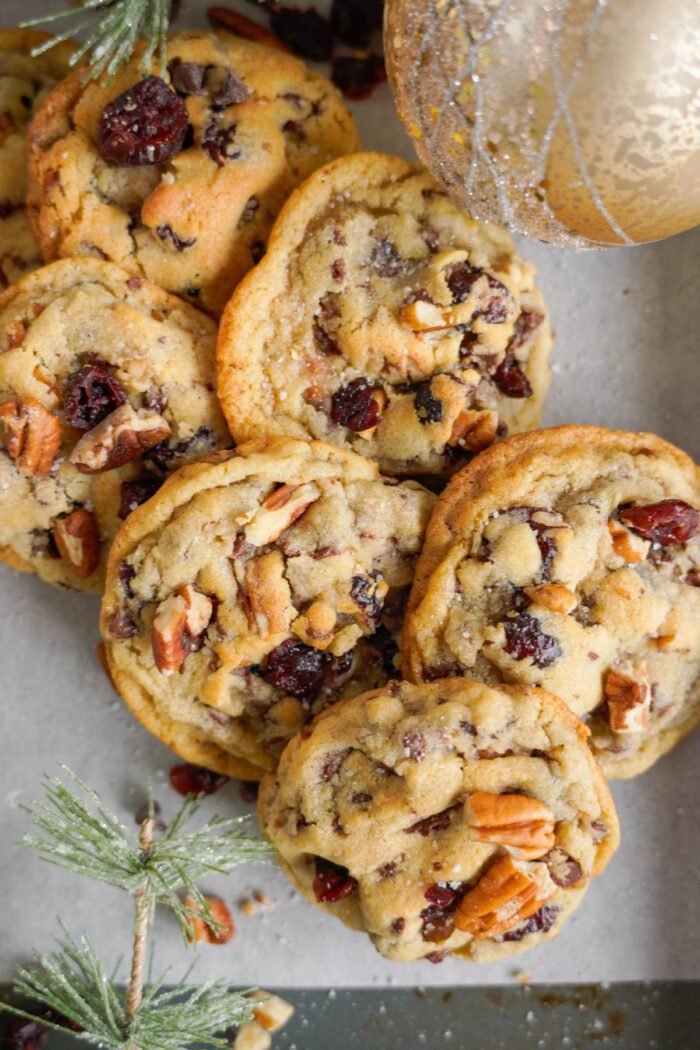 A close-up view of freshly baked cookies topped with nuts and dried cranberries.