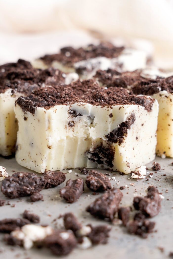 Slices of Oreo Fudge with cookie crumbles on top, displayed on a light surface.