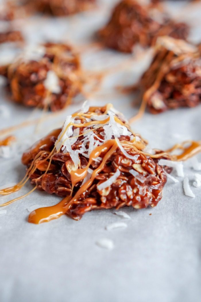 Close-up of a chocolate no bake cookie topped with shredded coconut, arranged on a baking sheet.