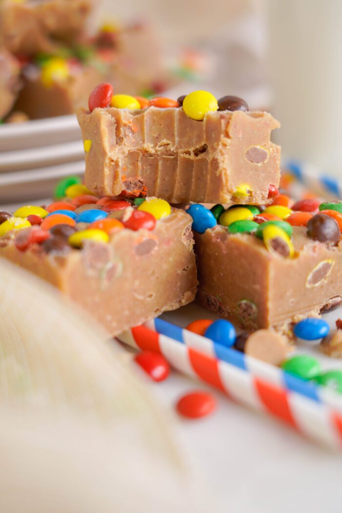 Slices of peanut butter fudge topped with colorful candy coated chocolates on a white plate.