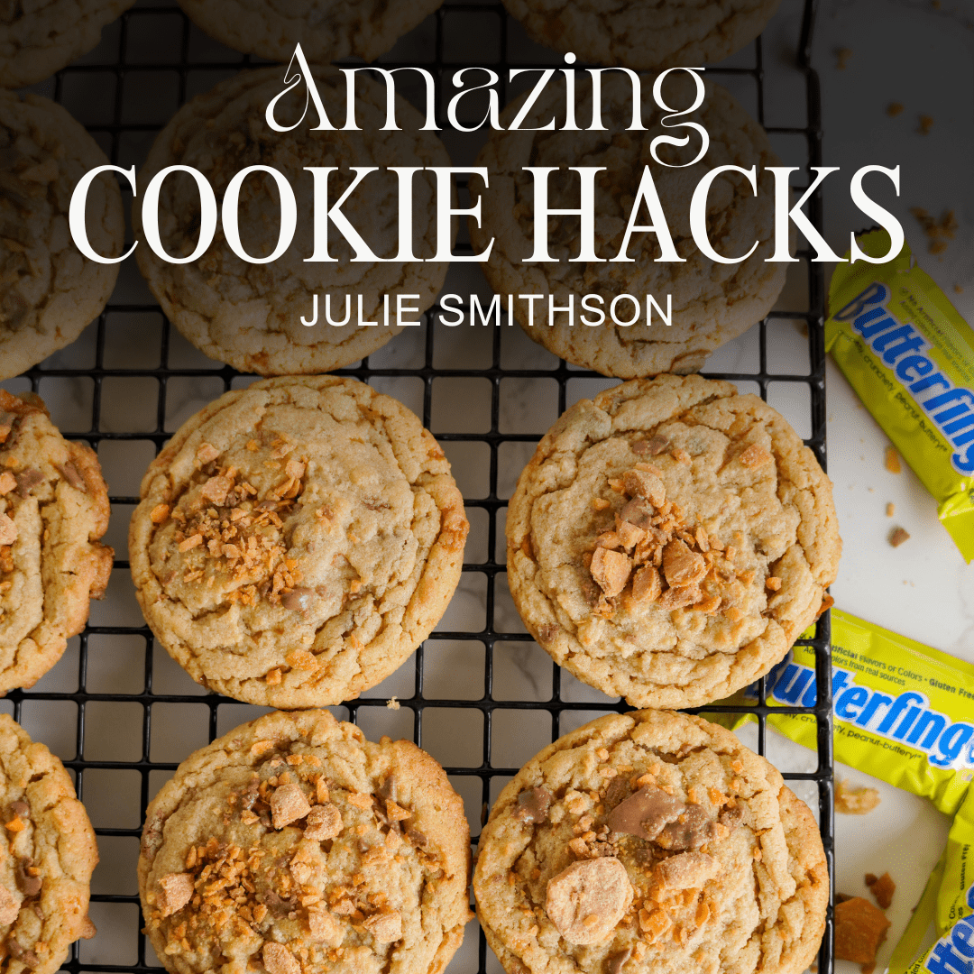 A cooling rack with cookies topped with crushed treats. The text reads "Amazing Cookie Hacks" by Julie Smithson, with Butterfinger candy bars beside the cookies.